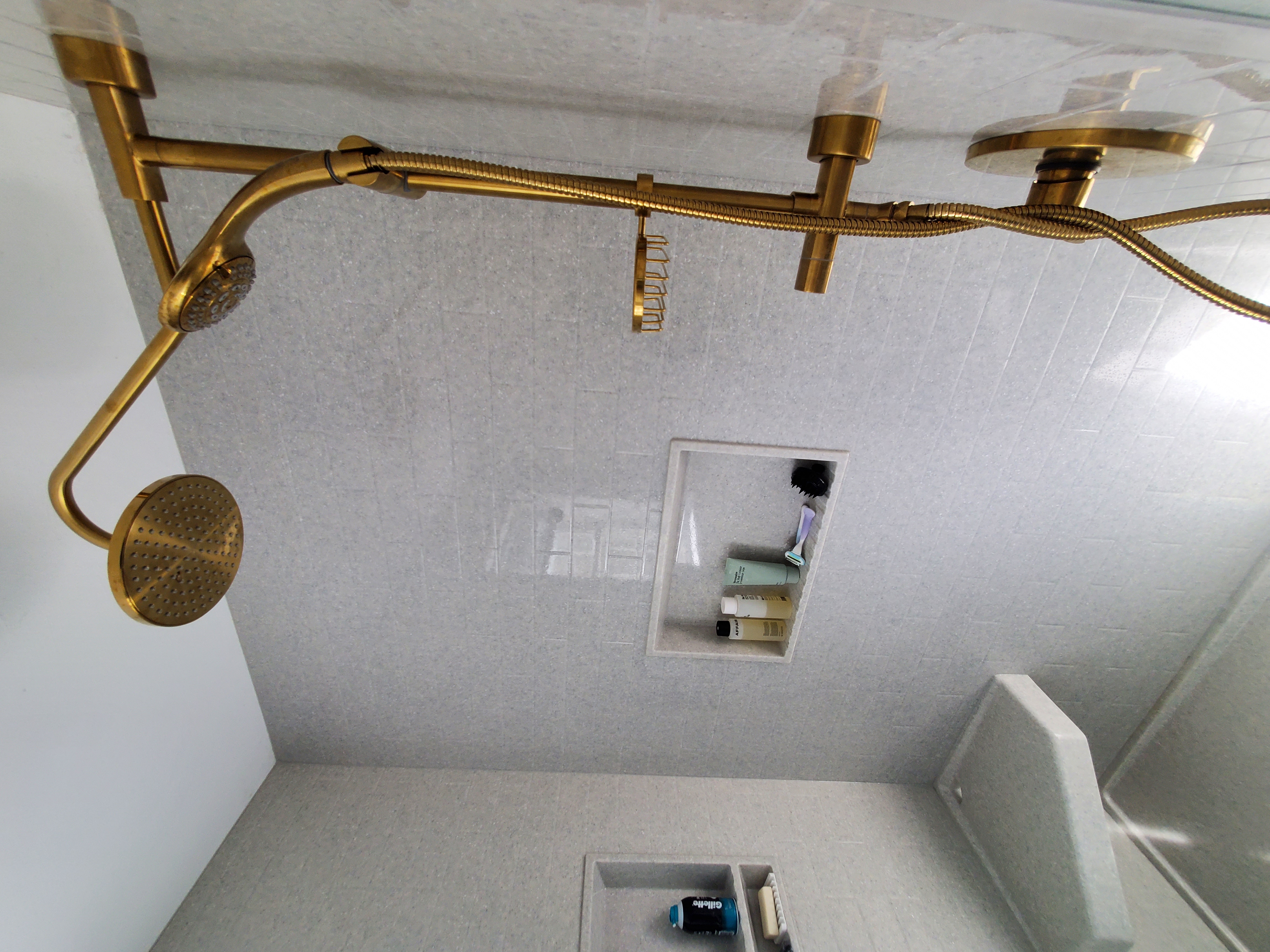 Custom stone panel shower with bench and shelves and fancy brass fixtures