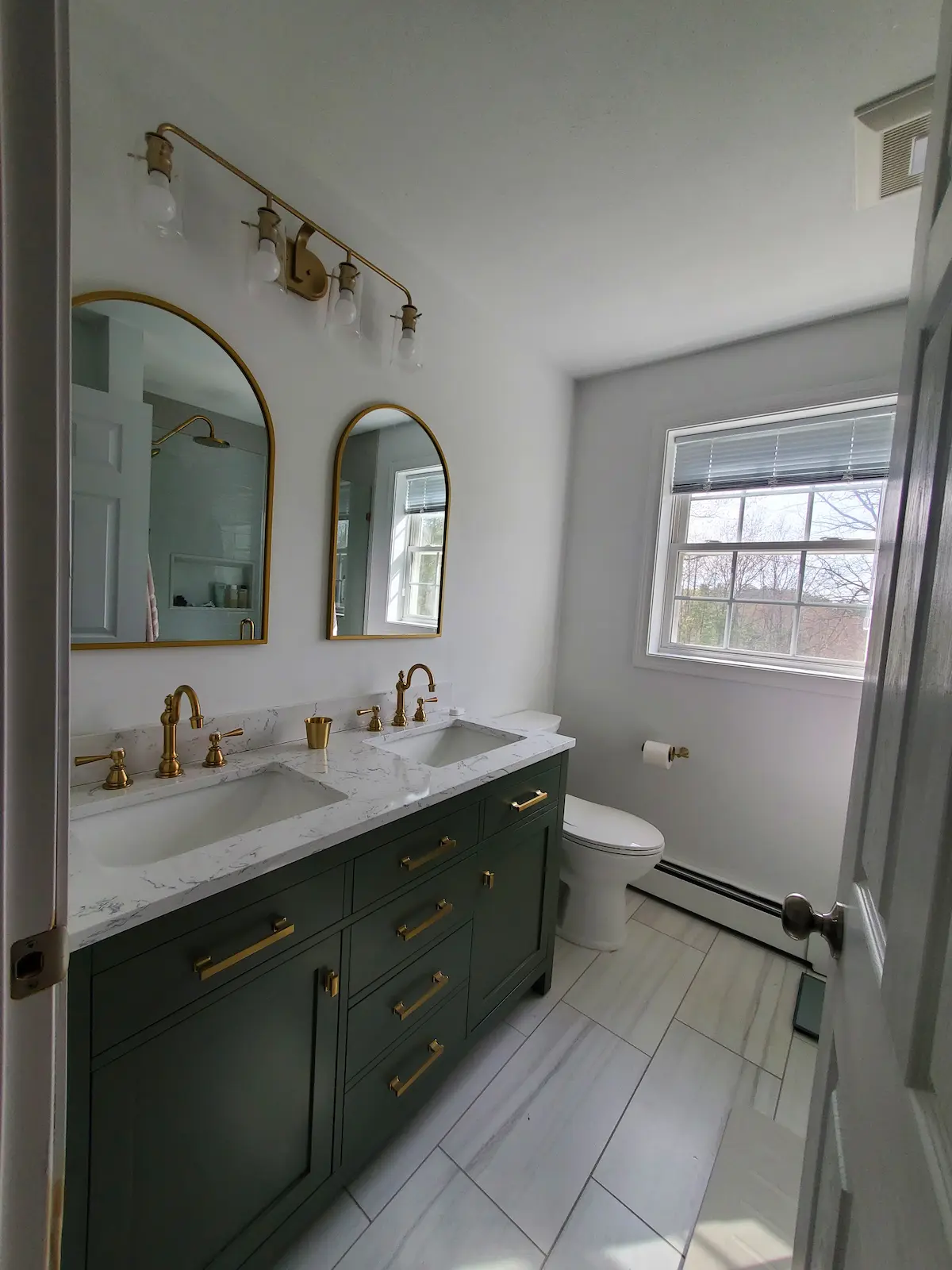 Beautifully remodeled bathroom with brass fixtures and porcelain tile in NH