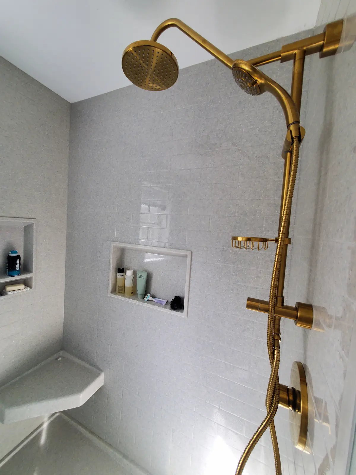 Custom stone panel shower with bench and shelves and fancy brass fixtures
